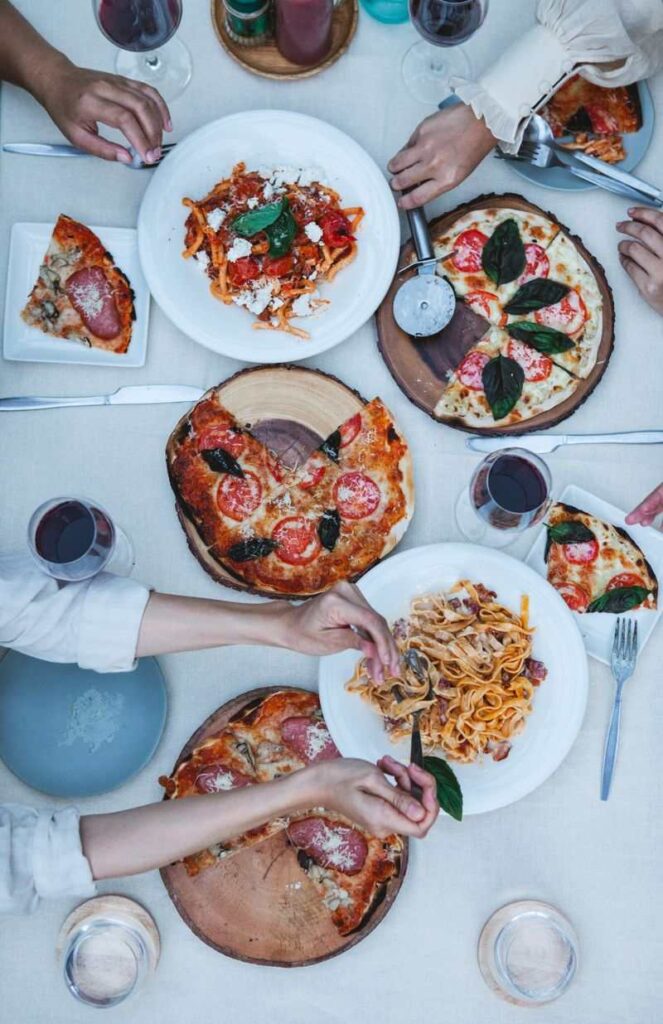 Chọn Rượu Vang Cho Tiệc Cưới Theo Ngân Sách: Tính Bao Nhiêu Chai Là Đủ? 1 Bàn tiệc món Ý với pizza, pasta và rượu vang đỏ