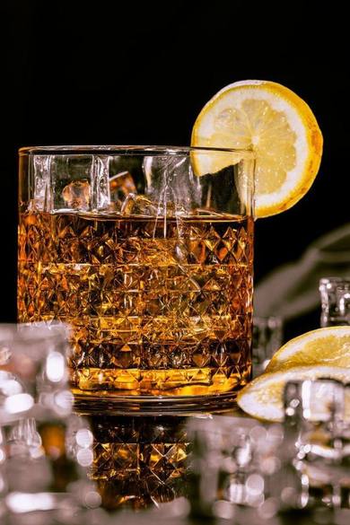 Ly cocktail cognac với đá và lát chanh trên nền đen