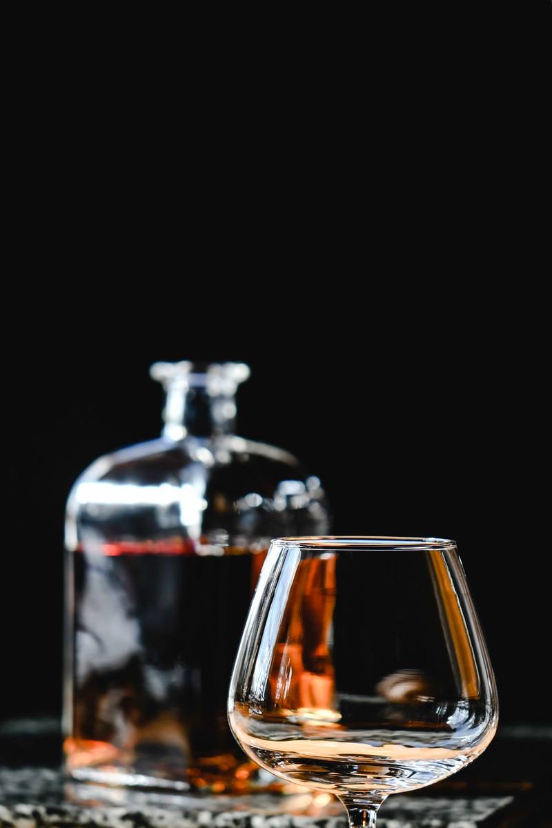 Ly rượu Brandy đặt cạnh chai rượu trên bàn gỗ