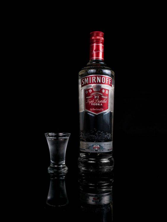 Chai vodka Smirnoff và ly shot trên nền đen sang trọng
